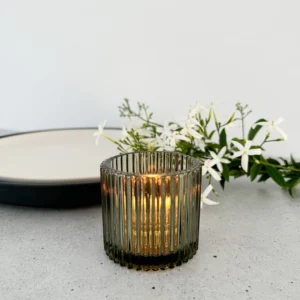 A green glass candle votive candleholder on a bench,